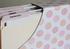 a stack of folders sitting on top of a pink polka dot covered table cloth