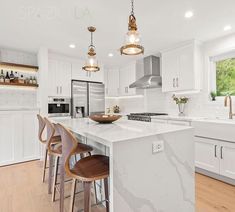 a large kitchen with white cabinets and marble counter tops, along with bar stools