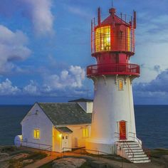 a red and white light house sitting on top of a cliff next to the ocean