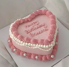 a heart shaped birthday cake with pink frosting