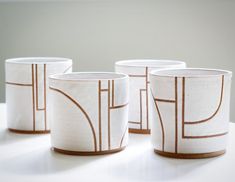 three white and brown cups sitting on top of a table