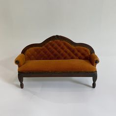 an orange couch sitting on top of a white floor next to a wooden frame and foot rest