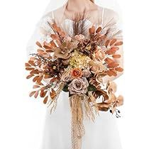 a woman in a wedding dress holding a bridal bouquet with leaves and flowers on it