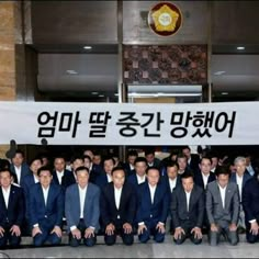 a group of men standing next to each other in front of a sign