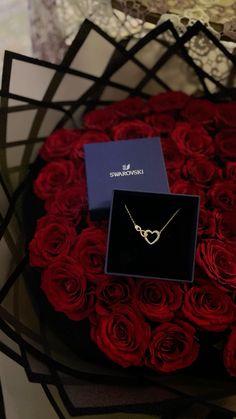 red roses in a black box with a necklace on it