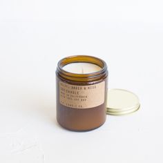 a candle sitting on top of a white table next to a small container with a brown lid