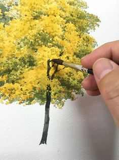 someone is painting a tree with yellow flowers