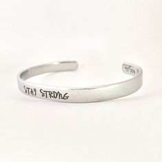 STAY STRONGThis inspirational hand stamped cuff bracelet makes the perfect gift to give or treat for yourself. The cuff is 1/4 inch by 6 inches and is bent to fit most wrists. My items are hand stamped by me, making them a unique gift. Each letter is stamped individually and may not line up exactly adding to the charm and uniqueness of the gift. Visit my shop to view all of my other items by clicking here: https://www.etsy.com/shop/GemsbyJohnnaPlease see my shop header for current production tim Personalized Inspirational Cuff Bracelet For Everyday, Everyday Inspirational Personalized Cuff Bracelet, Adjustable Personalized Cuff Bracelet For Everyday, Inspirational Stamped Adjustable Cuff Bracelet, Personalized Everyday Meaningful Cuff Bracelet, Inspirational Adjustable Cuff Bracelet For Personalized Gift, Everyday Personalized Meaningful Cuff Bracelet, Inspirational Adjustable Stamped Cuff Bracelet, Hand Stamped Bangle Cuff Bracelet