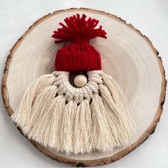 a red and white hat sitting on top of a piece of wood next to a wooden slice