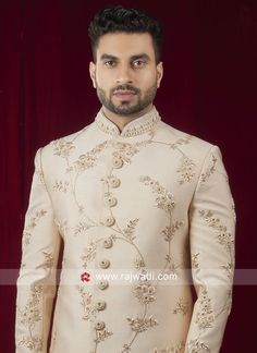 a man in a white sherve with gold embroidery on the chest and sleeves