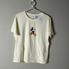 a mickey mouse t - shirt hanging on a hanger with a tag attached to it