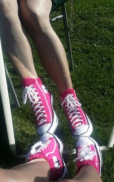 the legs and feet of a person wearing pink tennis shoes sitting on a lawn chair