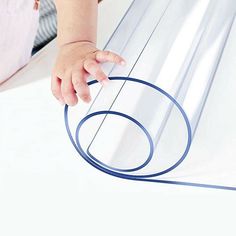 a baby's hand is on the edge of a sheet of clear plastic with blue lines