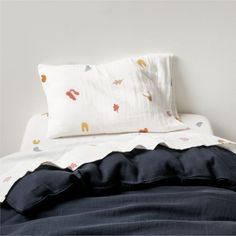 an unmade bed with two pillows on top of it and a white wall in the background