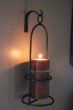 a candle that is sitting on a wall next to a light fixture with a wire around it