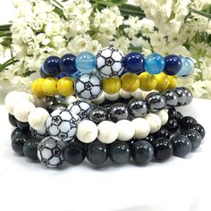 a stack of bracelets with black, white and yellow beaded balls on them