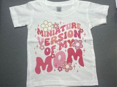 Celebrate the special bond between mother and child with our adorable "Miniature Version of Mom" t-shirt. Perfect for babies and toddlers, this tee is made from soft, high-quality fabric ensuring comfort for your little one. It's a perfect gift for Mother's Day, birthdays, or just because! Pink Screen Print T-shirt For Mother's Day, Playful Pink Tops For Mother's Day, Customizable Cute Spring Tops, Cute Customizable Spring Tops, White Fun T-shirt For Mother's Day, Customizable Playful Pink T-shirt, Cute Pink T-shirt For Mother's Day, Mother's Day Gift Top, Playful Name Print T-shirt For Mother's Day