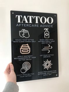 a sign that says tattoo aftercare advice on the side of a wall in front of a person's hand