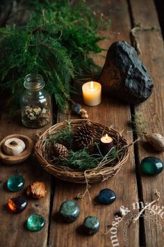 a basket filled with rocks and candles on top of a wooden table next to plants