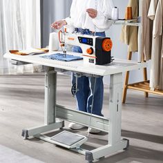 a man standing at a sewing machine with his hands on the table while he is using it