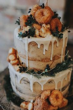 a three tiered cake with donuts on top and icing drizzled over it