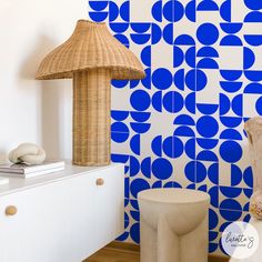 a room with blue and white wallpaper on the walls, a lamp and stools