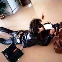 a woman laying on the floor with her purse and cell phone in front of her