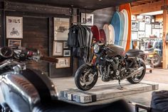 there is a motorcycle that is on display in the shop with surfboards behind it