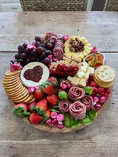 a wooden platter filled with cheese, crackers and fruit