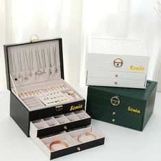 two black and white boxes with jewelry in them sitting on a table next to each other