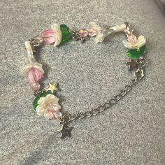 a close up of a bracelet on a person's arm with flowers and stars