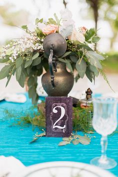 a table topped with a vase filled with flowers next to a wooden sign that says 2