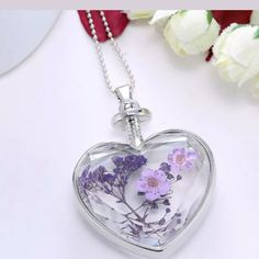 a glass heart shaped necklace with flowers inside