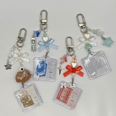 six different key chains with tags attached to them on a white surface, one has a red bow and the other is a blue heart