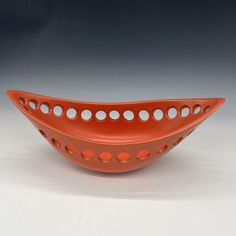 an orange bowl with holes in the middle