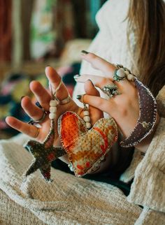 a woman with her hands in the air holding two star shaped rings and bracelets