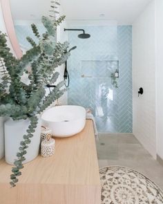 a bathroom with a sink, toilet and shower in the corner next to a potted plant