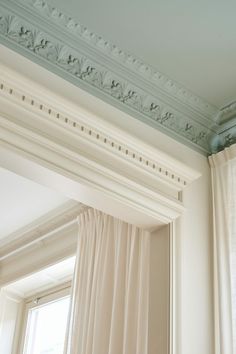 a white curtain is hanging in front of a window with a blue tint on the ceiling