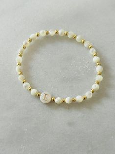 - Beautiful dainty pearl initial bracelet that makes a gorgeous bracelet gift. Soft and delicate with tiny 18 gold filled beads and freshwater shell initial bead. Coordinating pieces in shop. Beaded on high quality stretch cord and secured. - 3mm 18k gold filled beads   4mm mother of pearl beads    8mm freshwater shell initial bead. - Purchase is sent in a white velvet drawstring jewelry bag, making the perfect bracelet gift for bridesmaid, bracelet for mom, anyone special or just yourself. - To care for your bracelet, please roll on and off wrist. Repeated stretching can wear the elastic over time. Avoid excessive contact with water and chemicals. - We highly recommend measuring your wrist before ordering. Please see our sizing guide in the listing photos.  - We strive to get orders out a Bracelet For Mom, Bridesmaid Bracelet Gift, Gold Pearl Bracelet, White Velvet, Bridesmaid Bracelet, Initial Bracelet, Gorgeous Bracelet, Jewelry Bags, Bracelet Gift