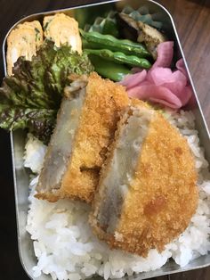 a bento box with rice, broccoli and meat on it sitting on a table