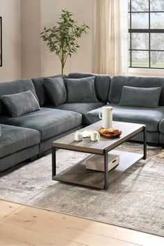 a living room with a couch, coffee table and rug in front of a window