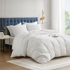 a bed with white linens and pillows in a room next to a large window