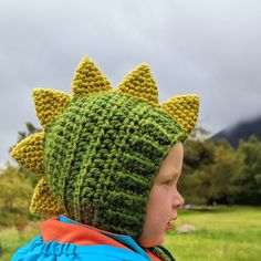 a child wearing a crocheted dinosaur hat