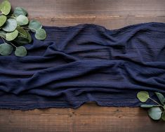 some green leaves are on top of a blue cloth that is laying on a wooden surface