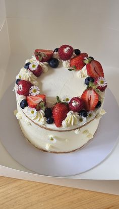 a white cake with strawberries and blueberries on top