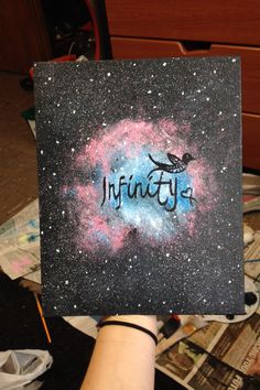 someone holding up a piece of art with the word infinite in space painted on it