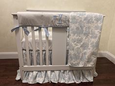 a baby crib with a blue and white bedding set on top of it