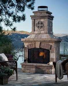 an outdoor fireplace with chairs around it