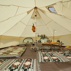 the inside of a large tent with several beds and pillows on it's floor