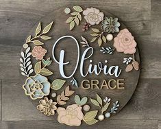 a sign that says flora grace with flowers and leaves around it on a wooden surface